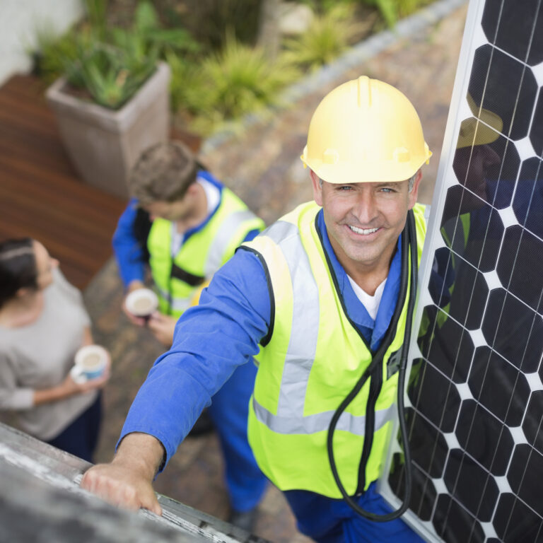 Worker installing solar panel on roof